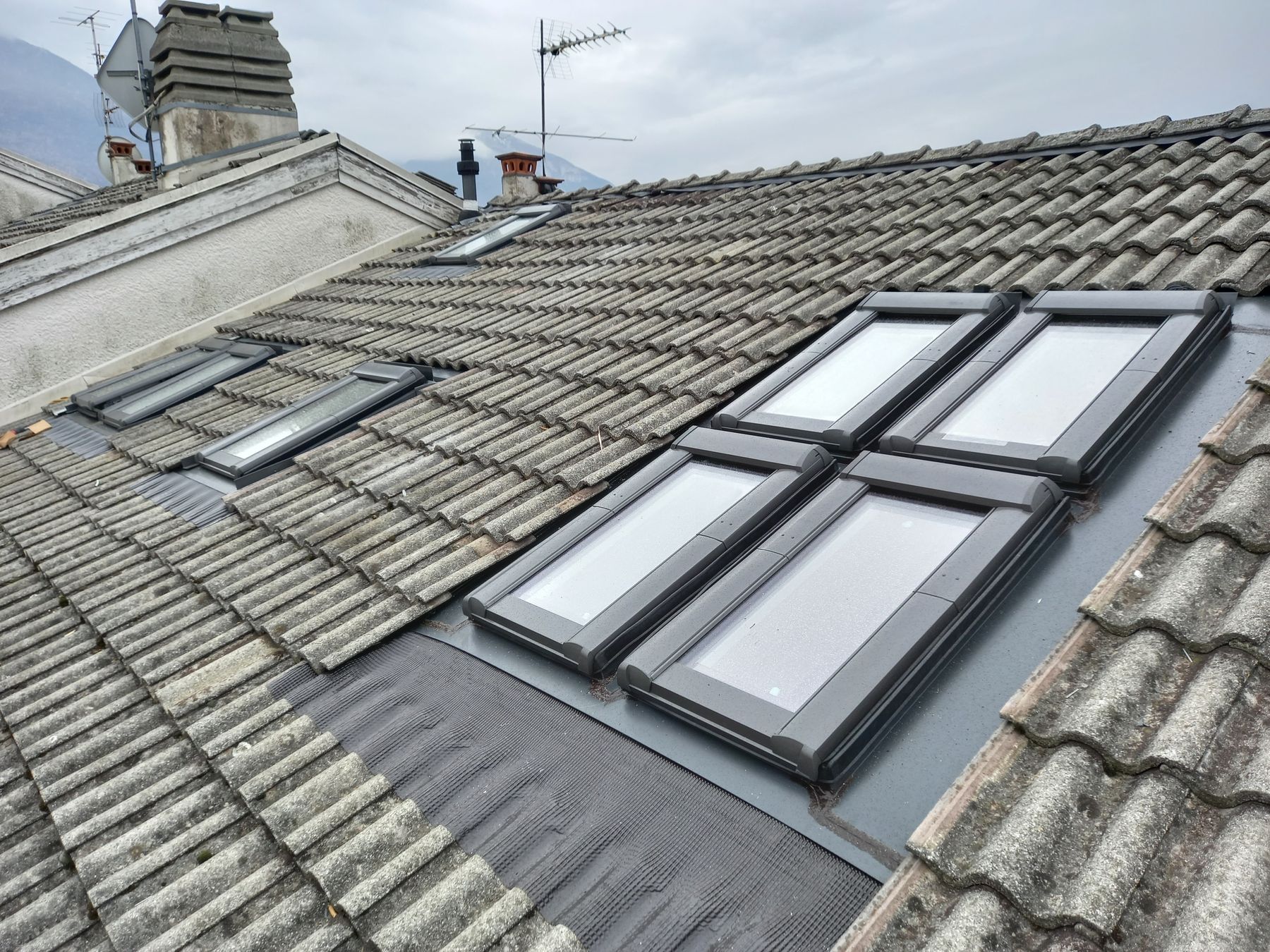 Quattro finestre per tetti ROTO Designo R6 accostate su un tetto con legni originali