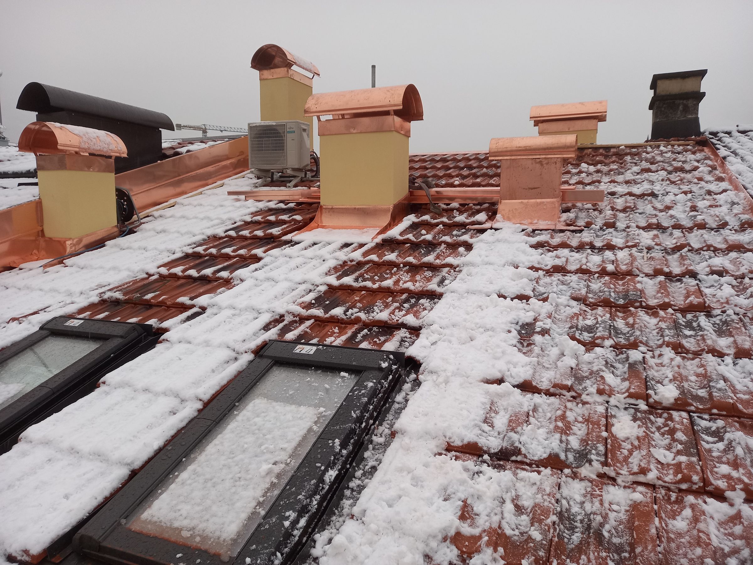 Lattonerie in rame e finestre per tetti su una copertura in coppi con la neve