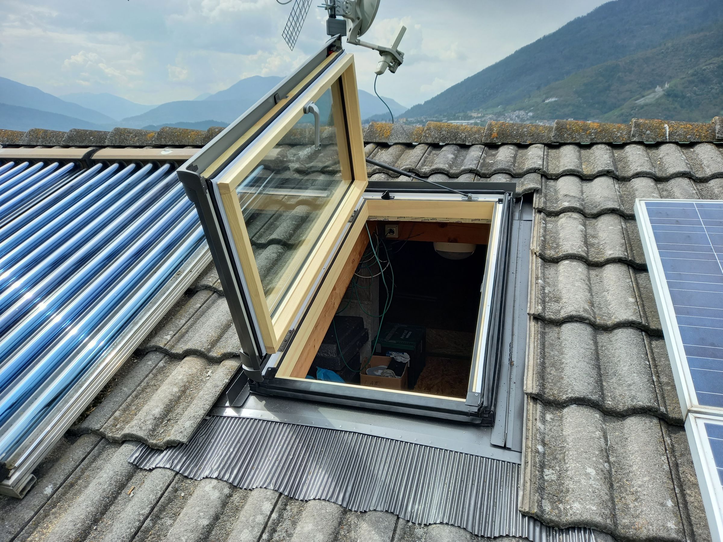 Uscita sul tetto ROTO in legno installata da Lattonerie Faes, con vista sulle montagne